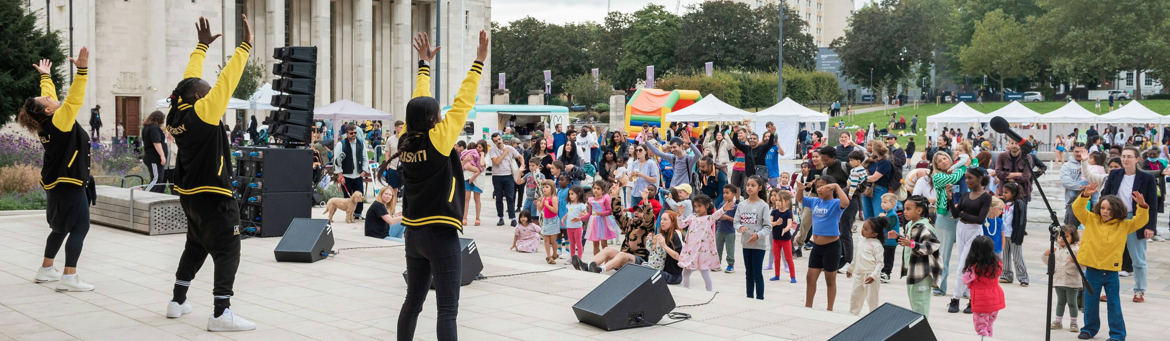 Three women dance in front of a crowd