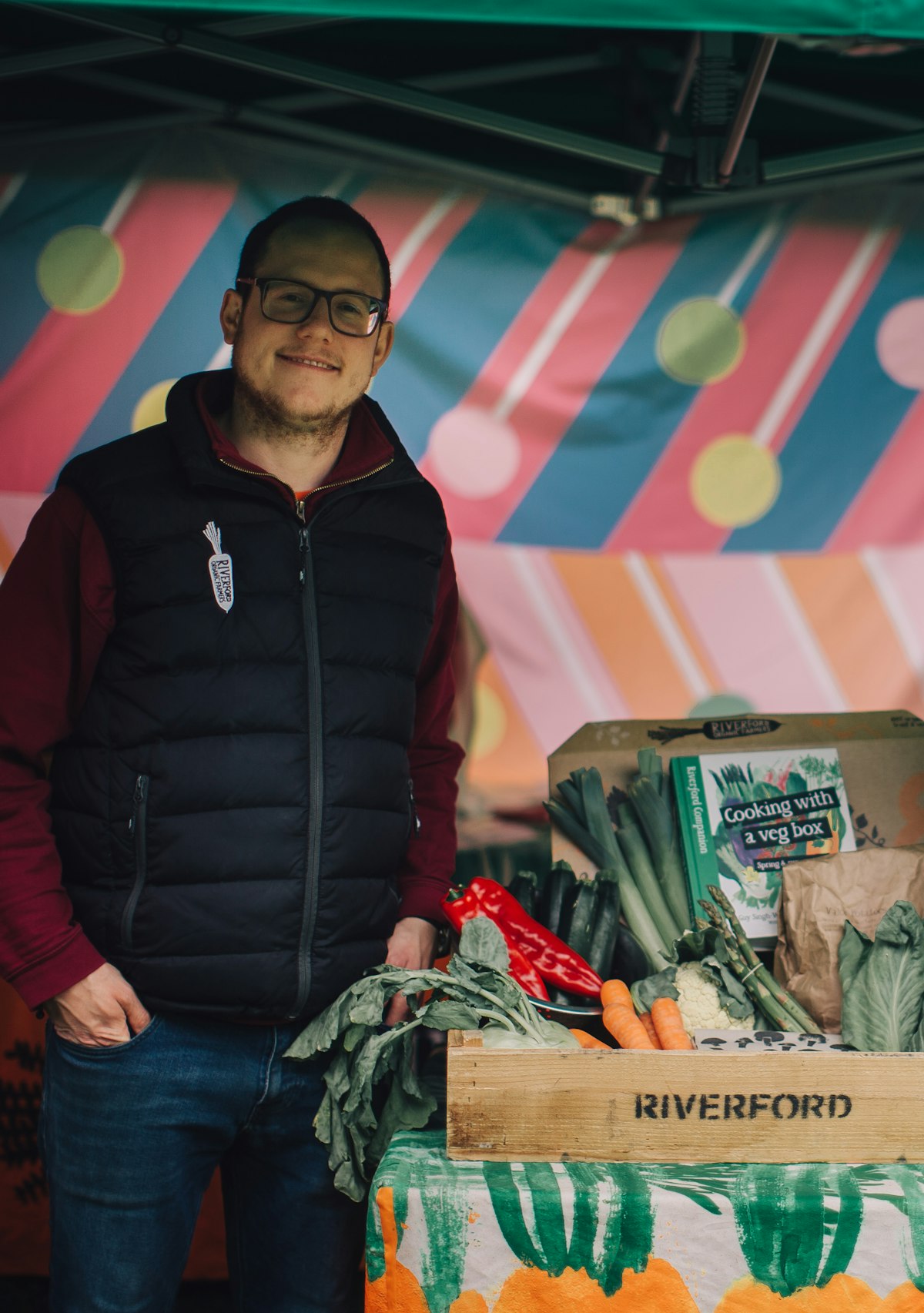 A market trader stands next to his stall of fruit and veg
