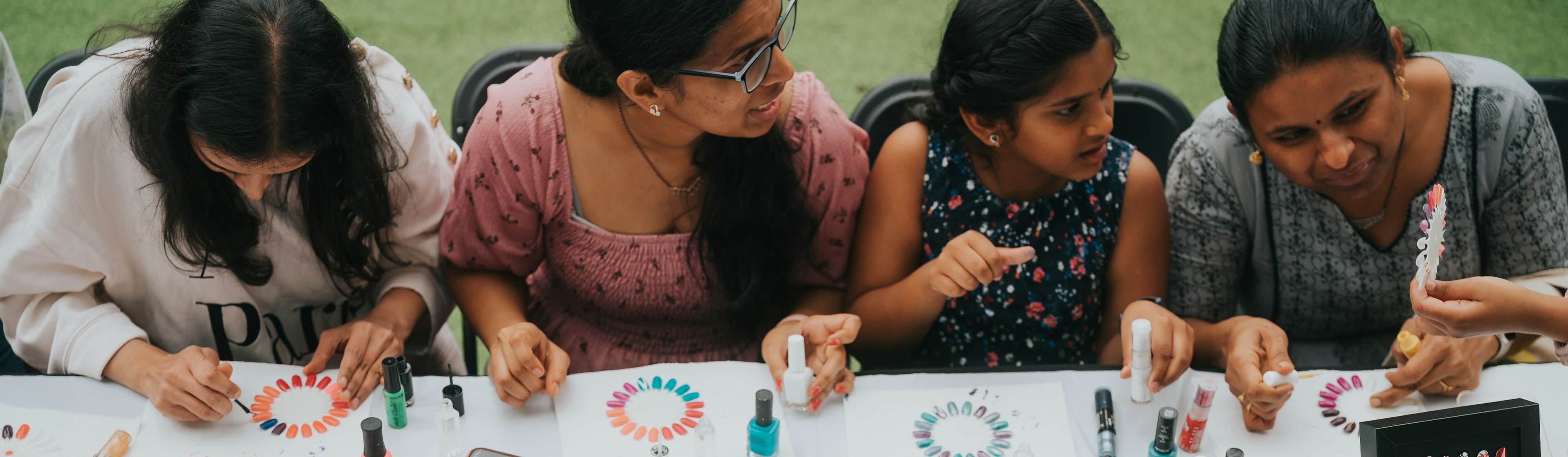 People sit at a table making nail art