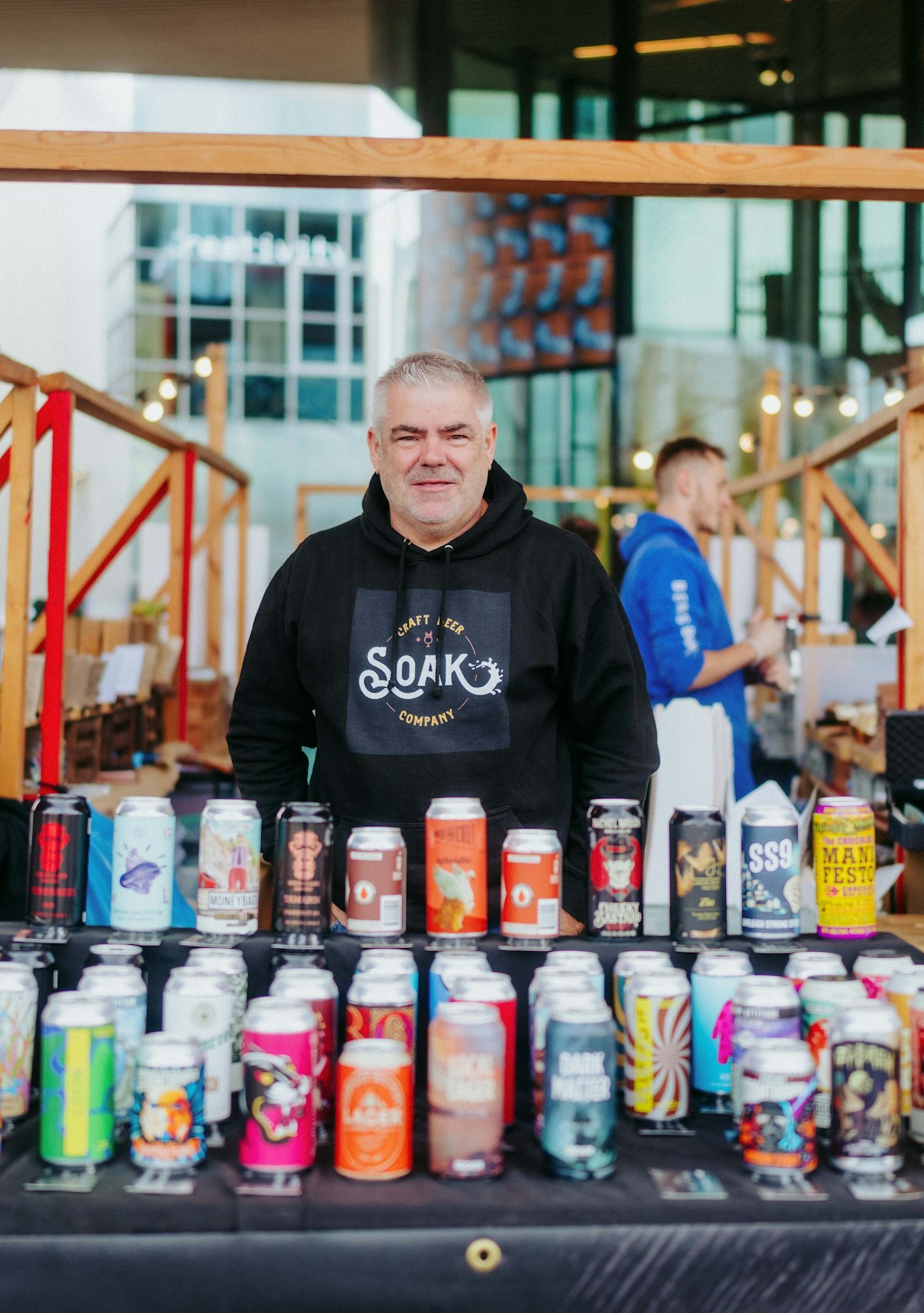 A man stands behind a selection of beers at the market stall