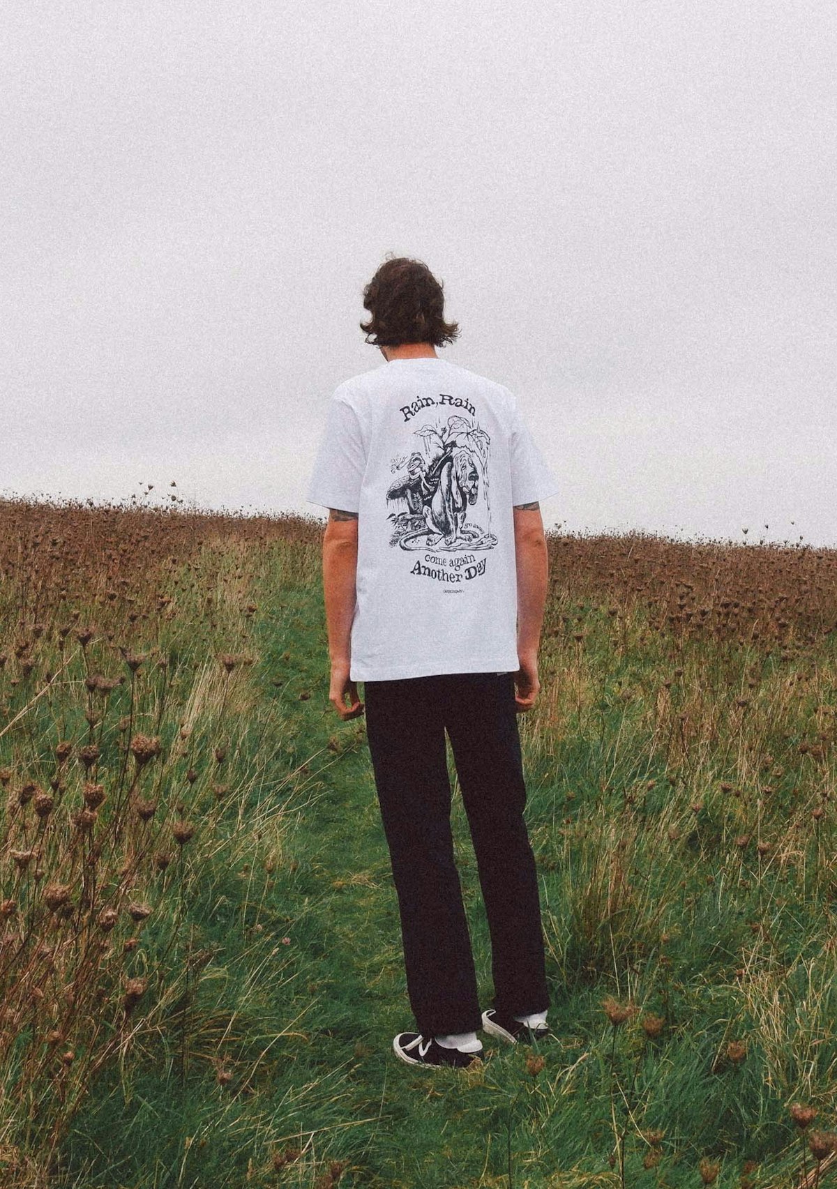 A man wears a white t-shirt with a slogan on the back