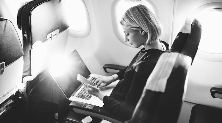 Empleado trabajando en un ordenador a bordo de un avión. Los viajes corporativos son una forma muy eficiente de transportar a los empleados de un sitio a otro en avión.