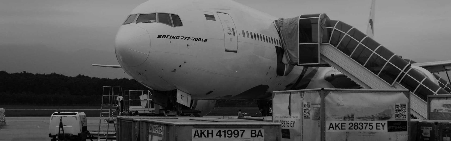 Two cargo containers in front of an aircraft boeing 777 300 ER that is waiting in the airport tarmac.