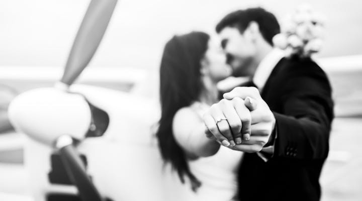 Pareja casada frente a un avión. Alquilar un avión para transportar a todos sus invitados para su ceremonia de boda