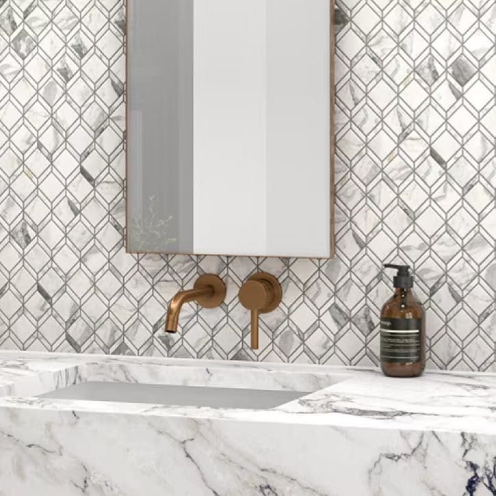 White and grey stone sink with pattern tiles behind it
