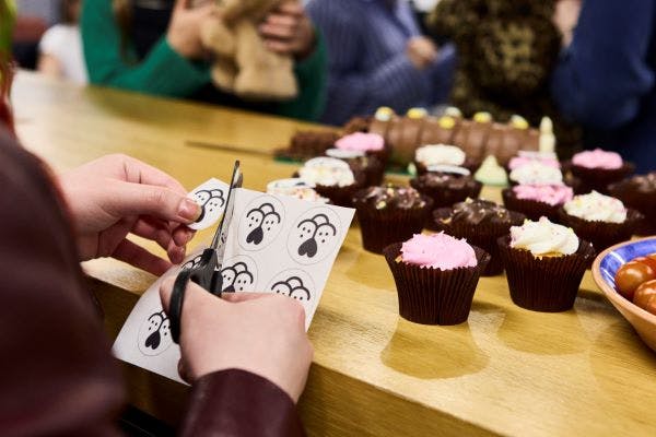 A person uses scissors to cut out a sheet of edible dog nose cake toppers.