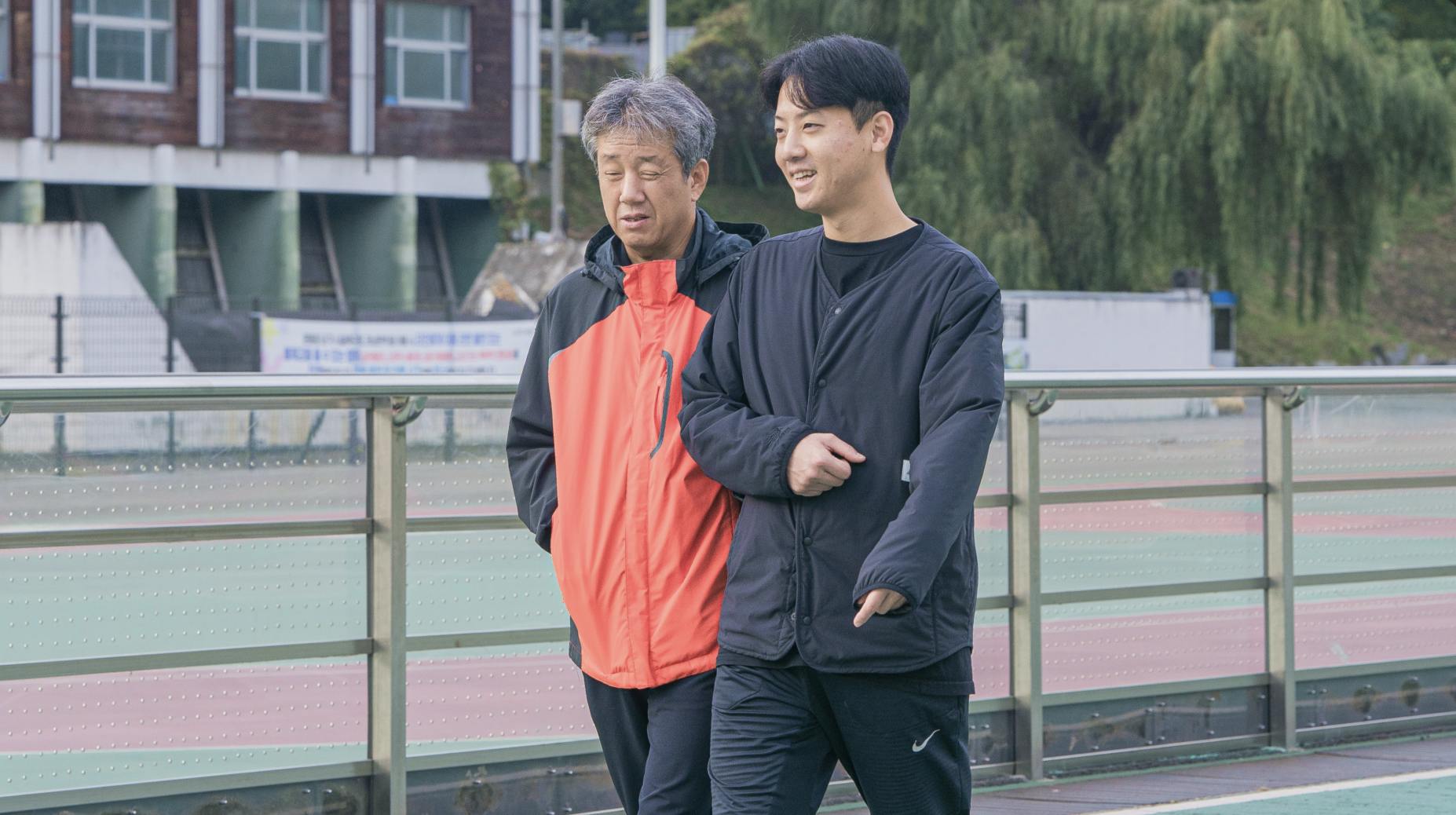 시각장애러너와 가이드러너가 서로 팔을 잡고 길을 걷고 있는 장면