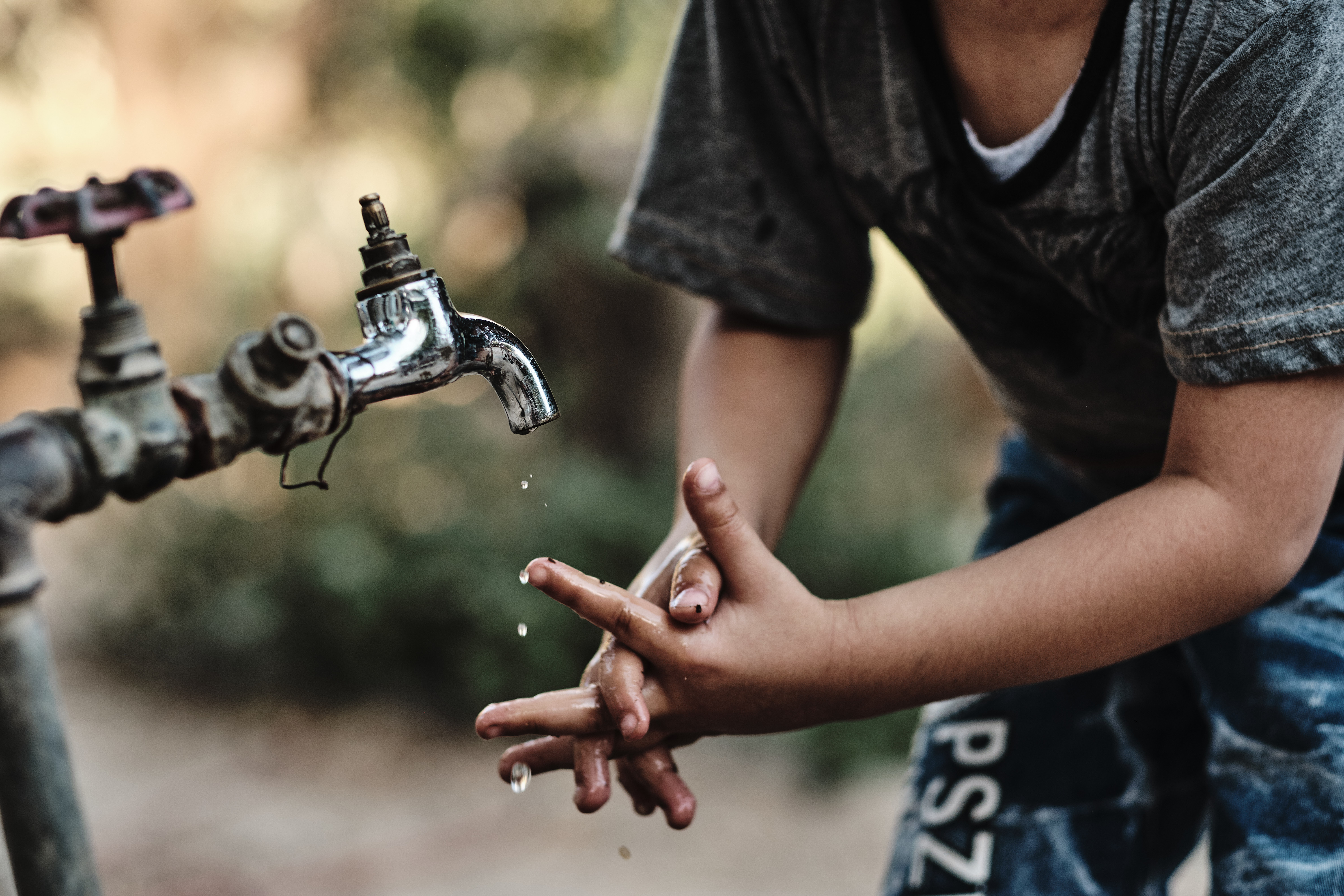 Child plays with water tap in local resident backyard, Azraq, Jordan. August 2019 Photograph: Guido van Helten