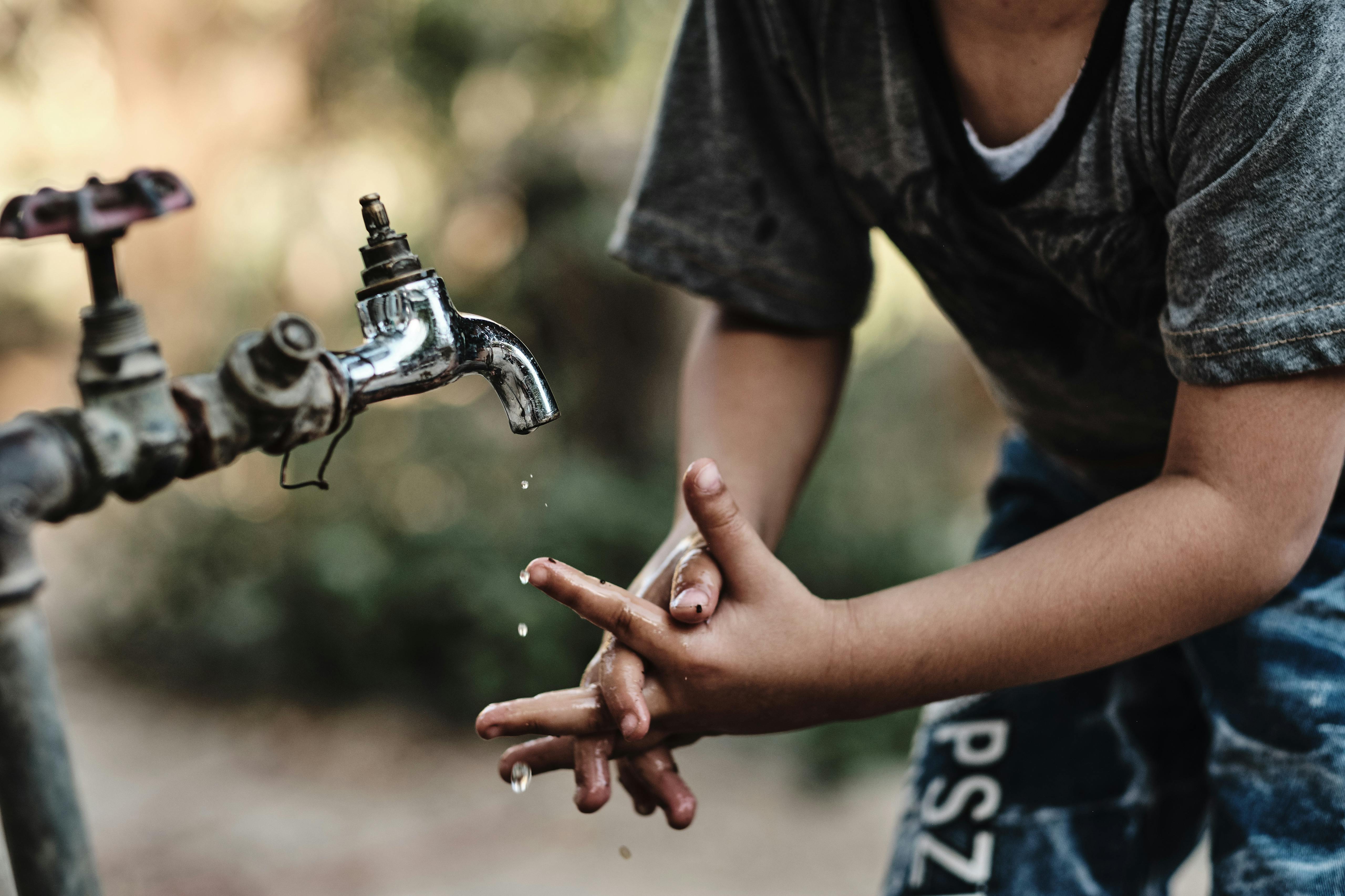 Child plays with water tap in local resident backyard, Azraq, Jordan. August 2019 Photograph: Guido van Helten
