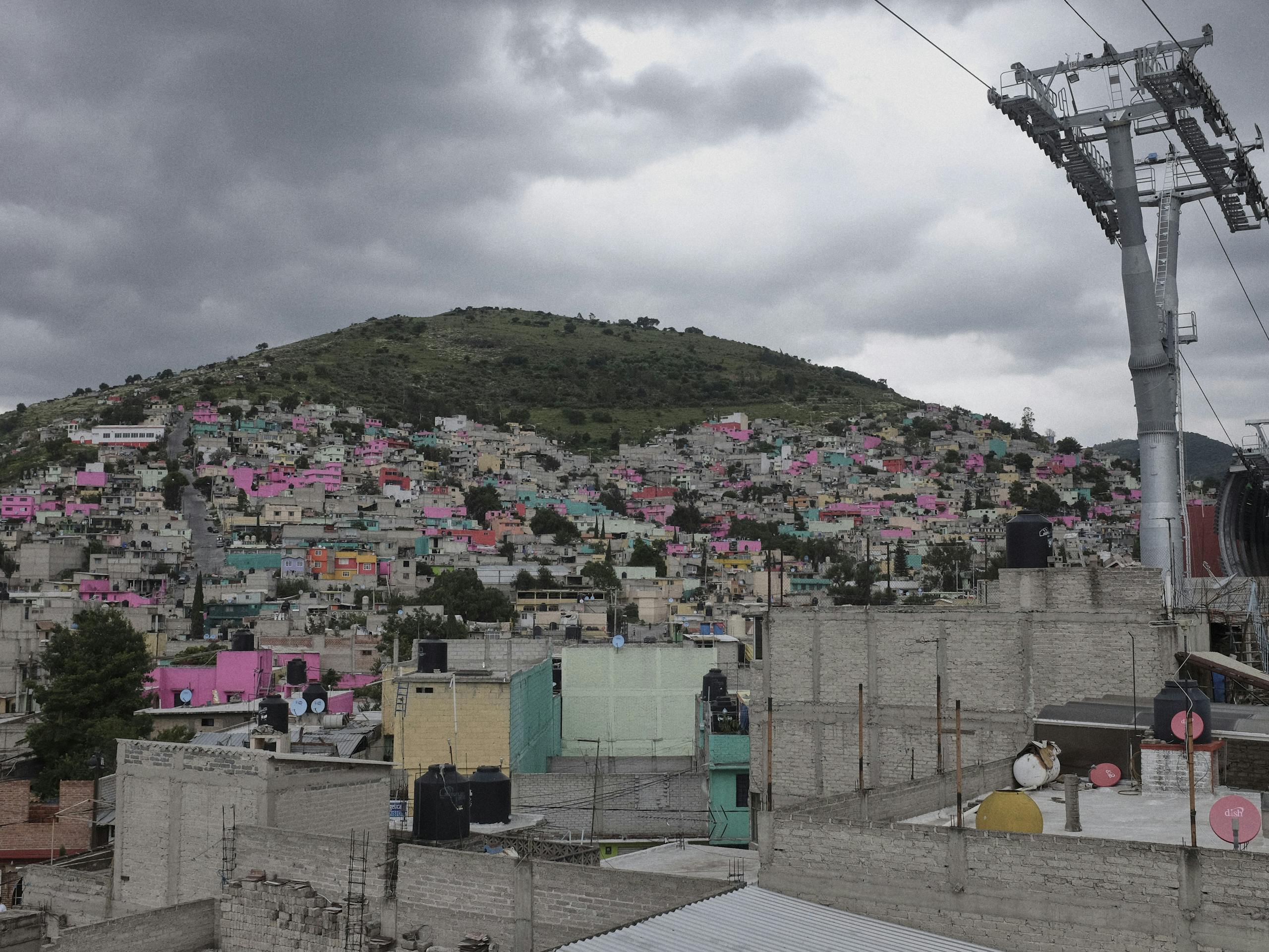 Cable car line runs through the most densely populated hills of the city, Ecatepec, Estado de México, Mexico. July 2016 Photograph: Guido van Helten