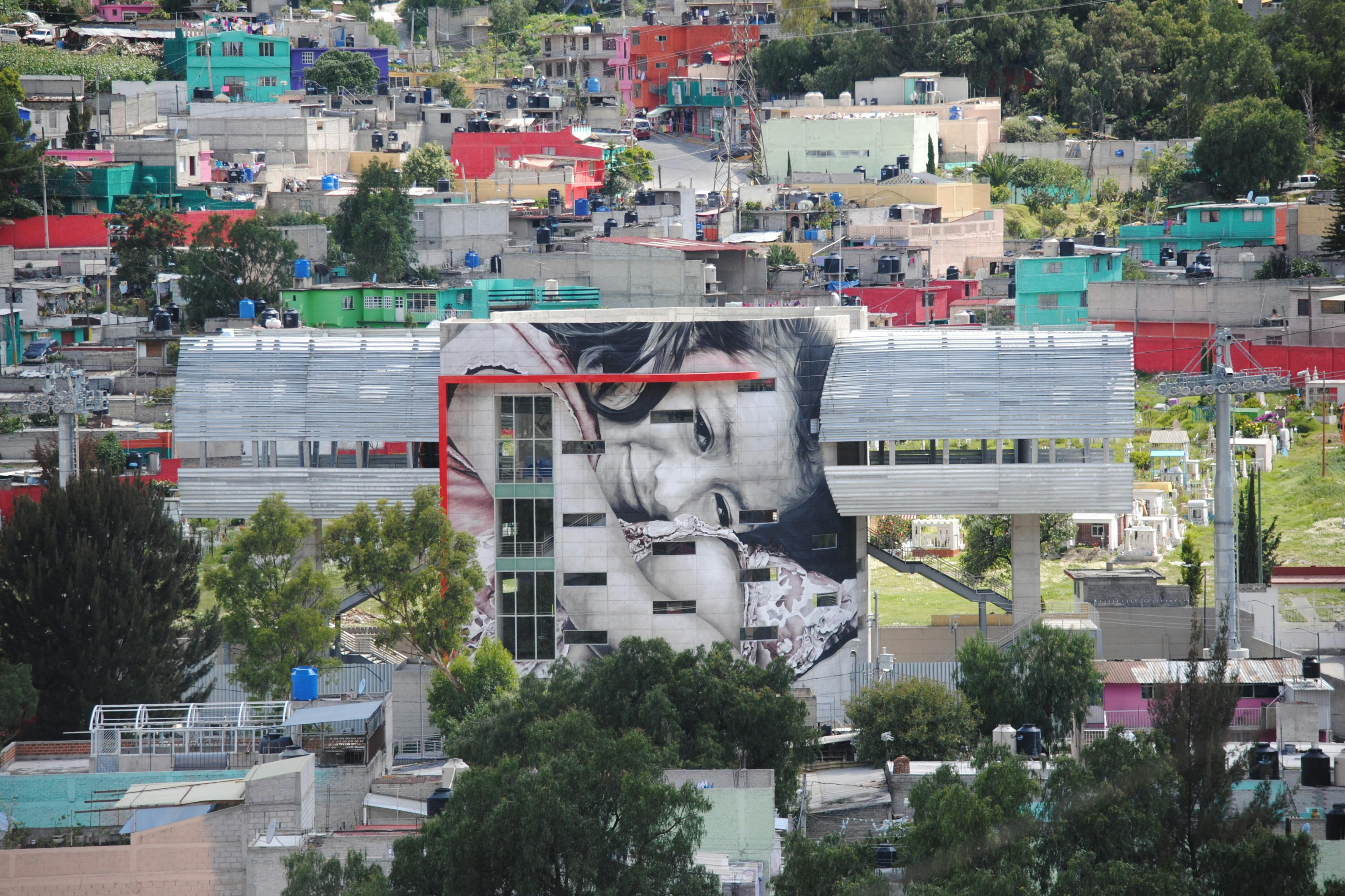 'Valeria' surrounded by the colourful concrete style house. Ecatepec, Estado de México, Mexico. July 2016 Photograph: Guido van Helten