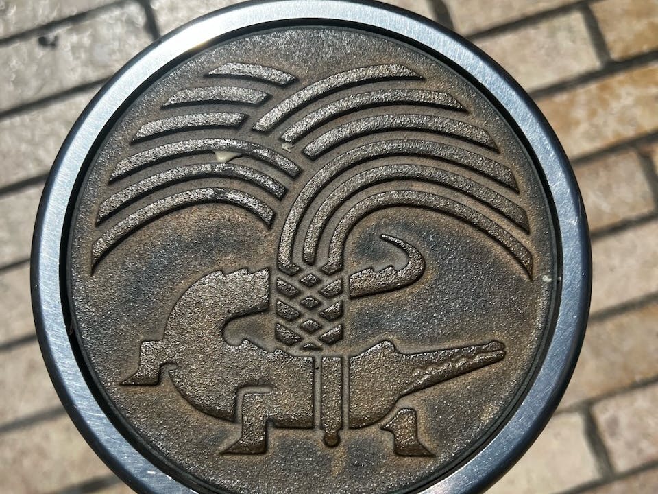 The palm tree is an old Roman symbol for victory, while the crocodile represents Egypt. The text, “Col Nem”, means Colonia Nemausus, or settlement of Nîmes. The emblem dates back to 1535