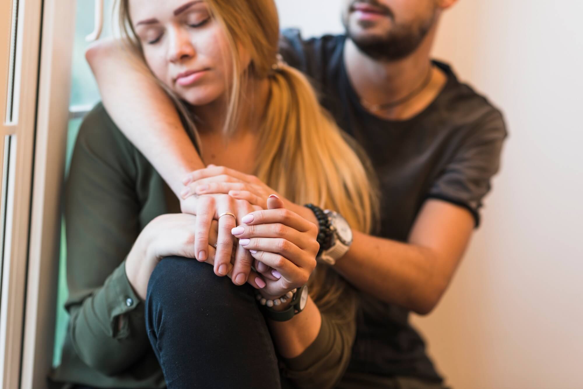 Frau und Mann sitzen hintereinander und umarmen sich