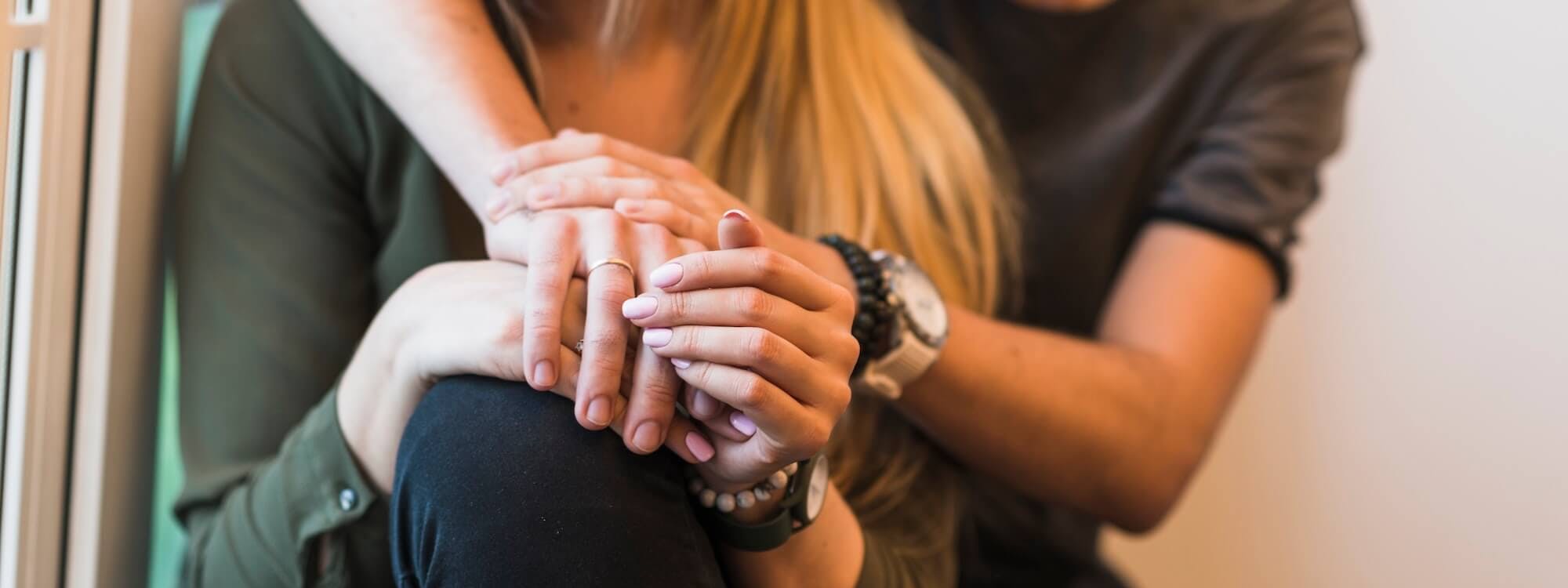 Frau und Mann sitzen hintereinander und umarmen sich