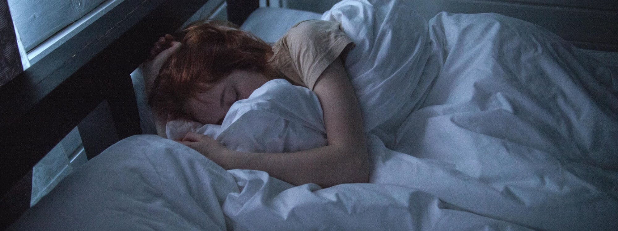 Frau liegt in ihrem Bett im dunklen Raum