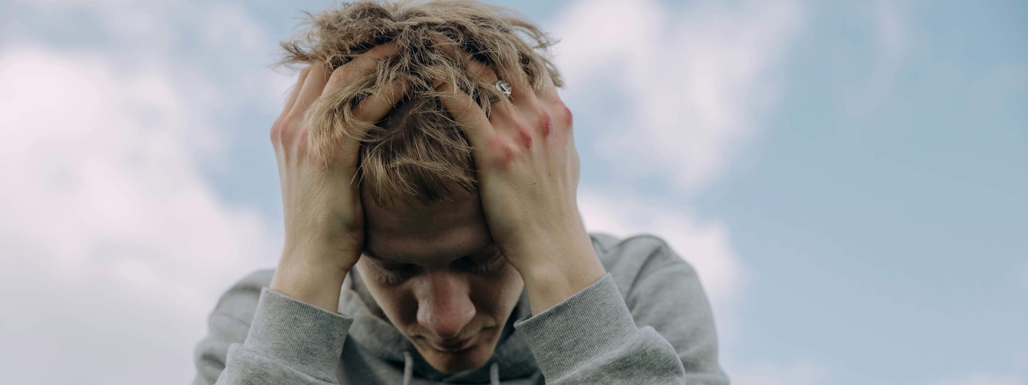 Junger Mann hält sich den Kopf vor Schmerzen