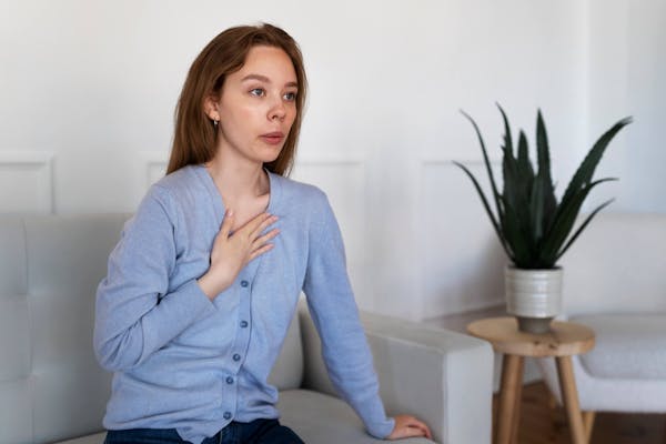 Frau sitzt auf Couch mit Panikattacke