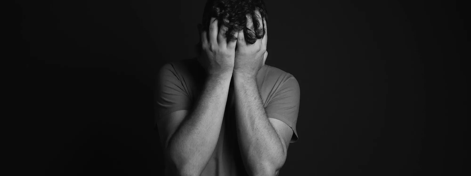 Mann hält seinen Kopf zwischen den Händen fest
