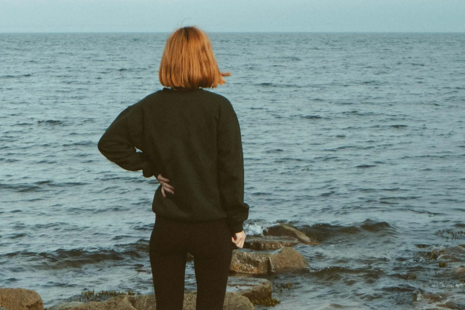 Frau steht am Rand vom Meer Frau steht am Rand vom Meer