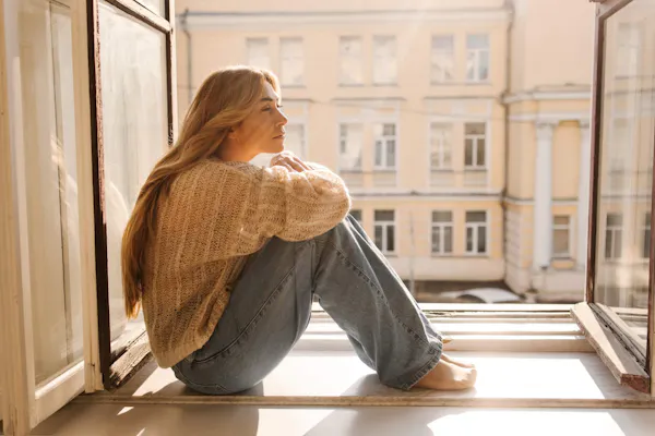 Frau sitzt nachdenklich am Fenster