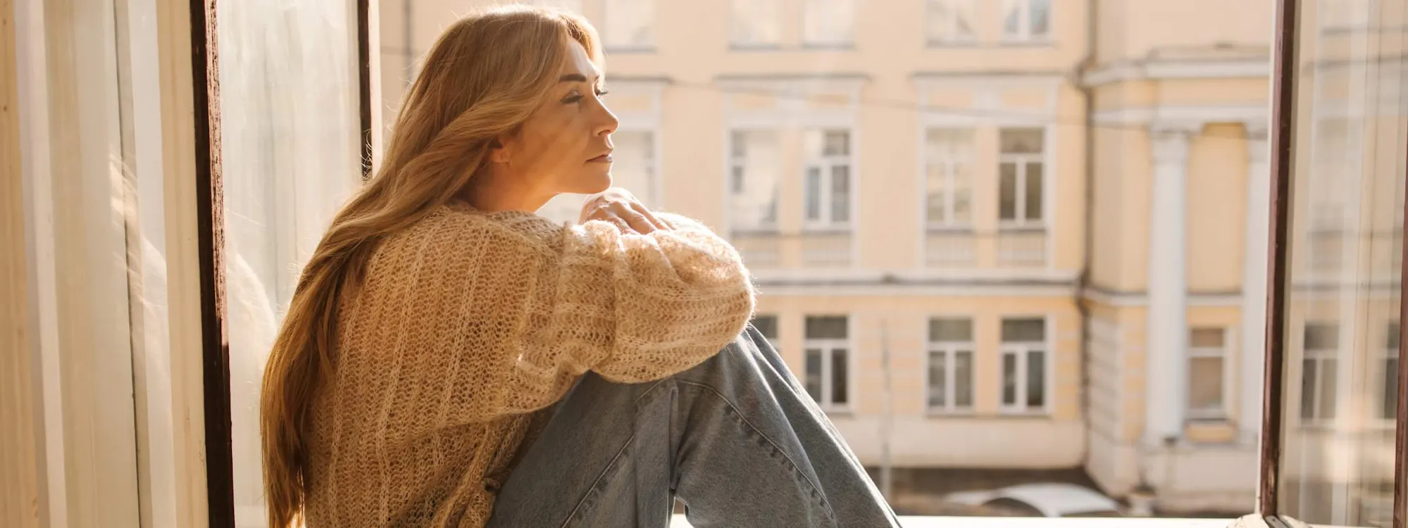 Frau sitzt nachdenklich am Fenster