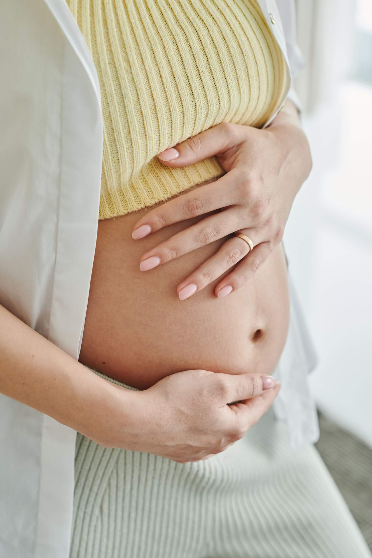 Schwangere Frau hält sich die Hände an den Bauch