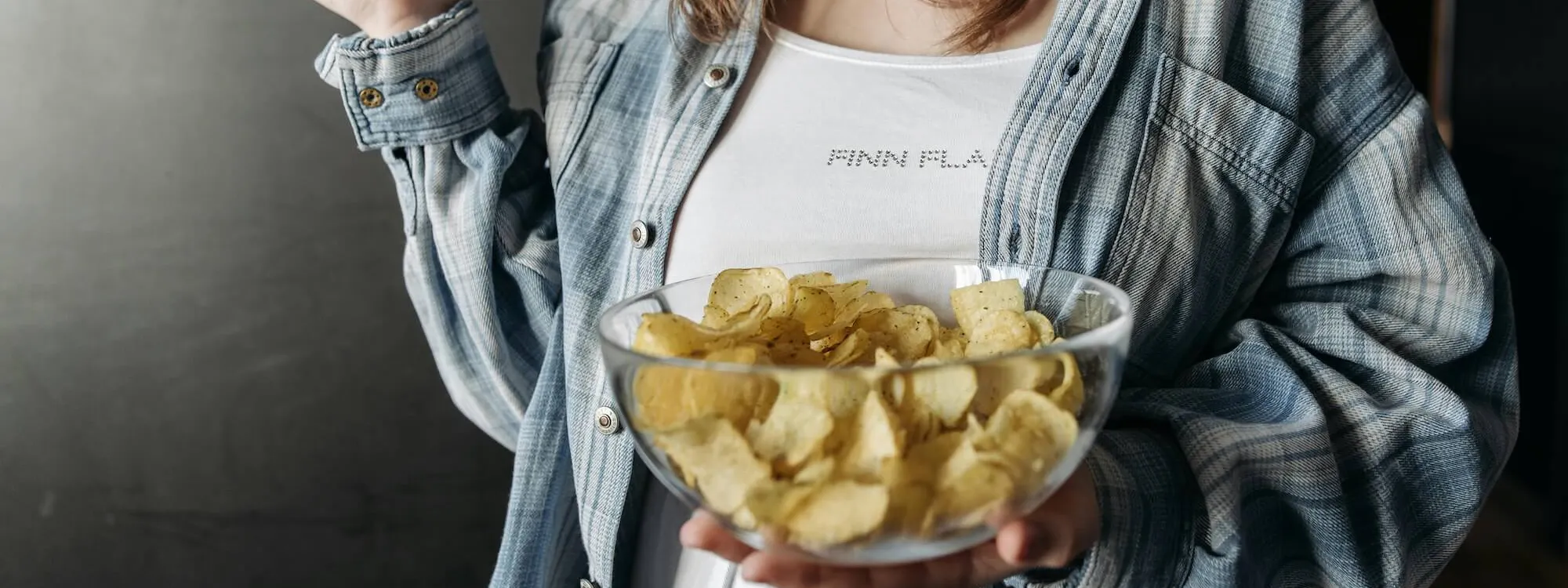 Frau isst Kartoffel Chips aus einer Glasschüssel