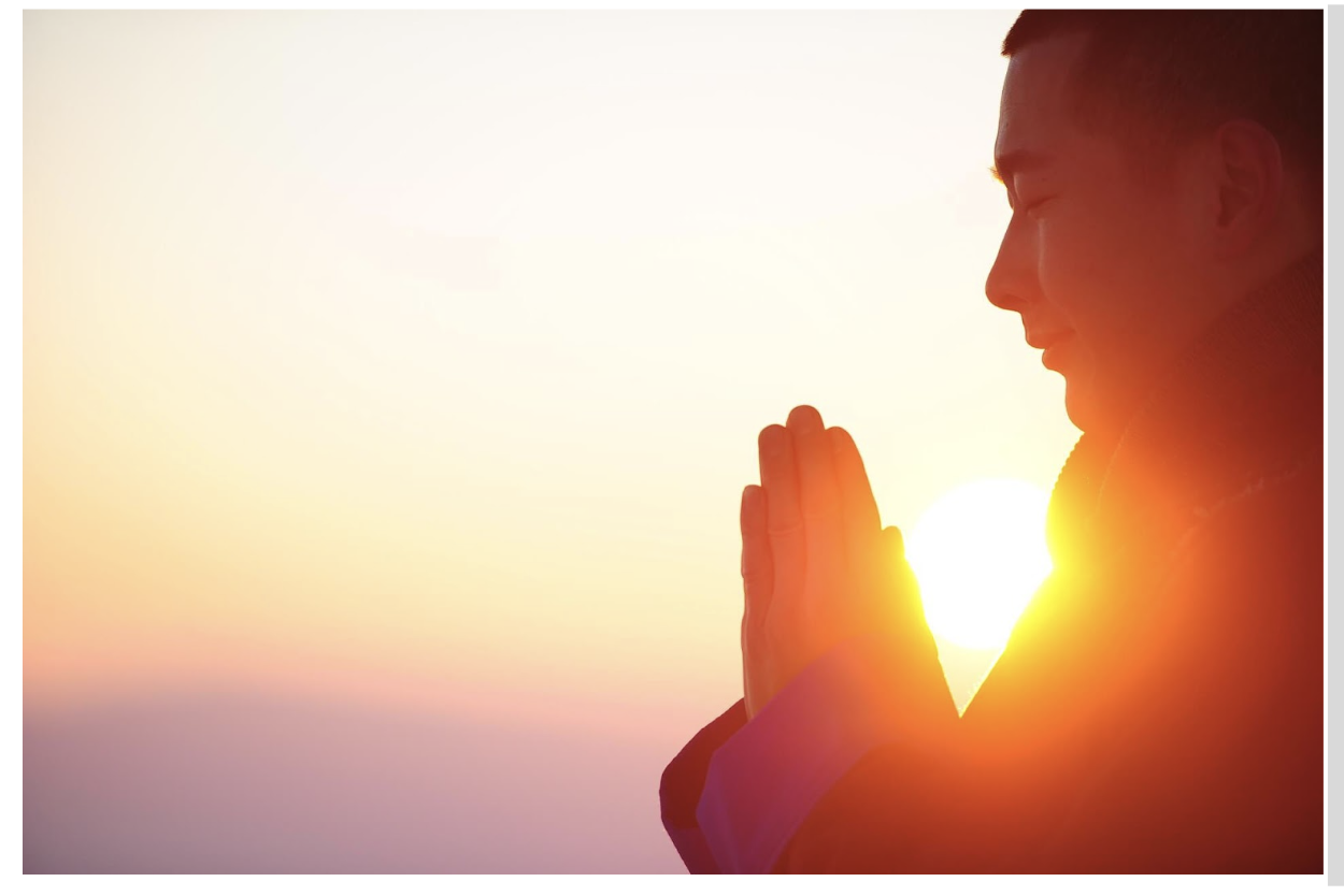 Mann meditiert beim Sonnenuntergang