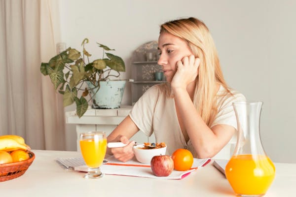 Frau sitzt mit gesundem Essen am Tisch
