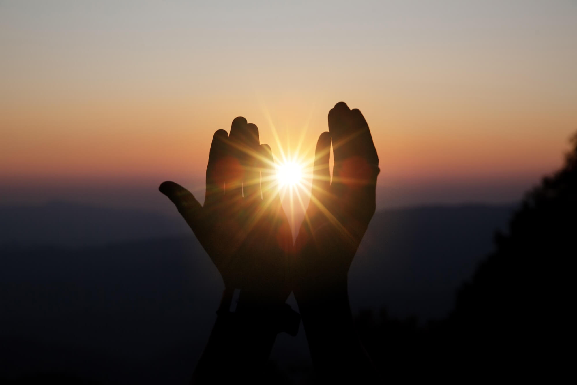 Hände werden vor den Sonnenuntergang gehalten