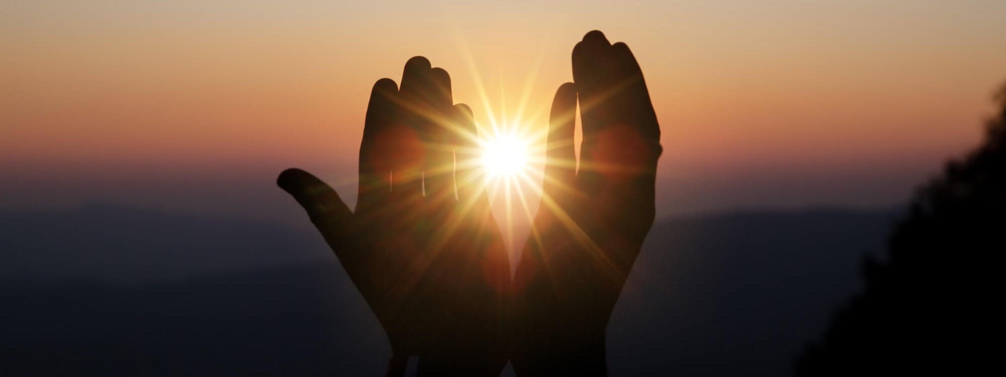 Hände werden vor den Sonnenuntergang gehalten