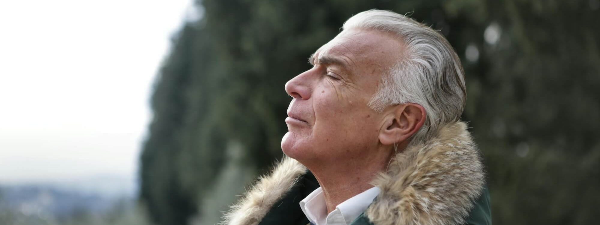 Mann steht in der Natur und atmet durch