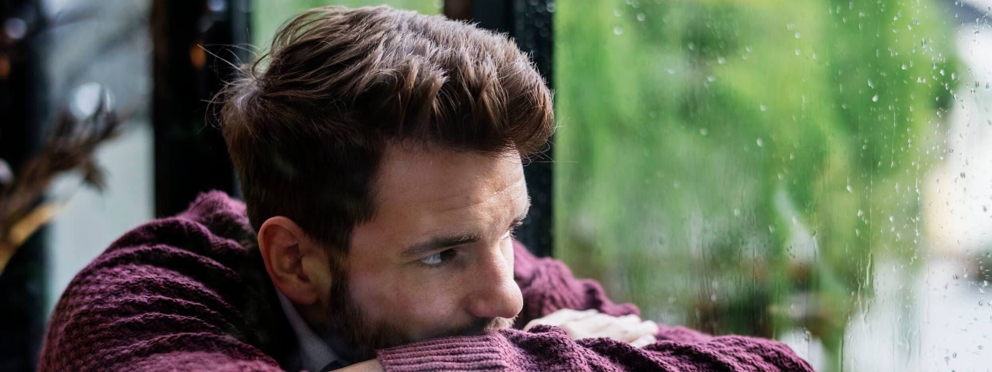 Mann schaut nachdenklich aus dem Fenster