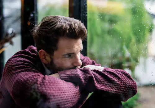Mann schaut nachdenklich aus dem Fenster Mann schaut nachdenklich aus dem Fenster