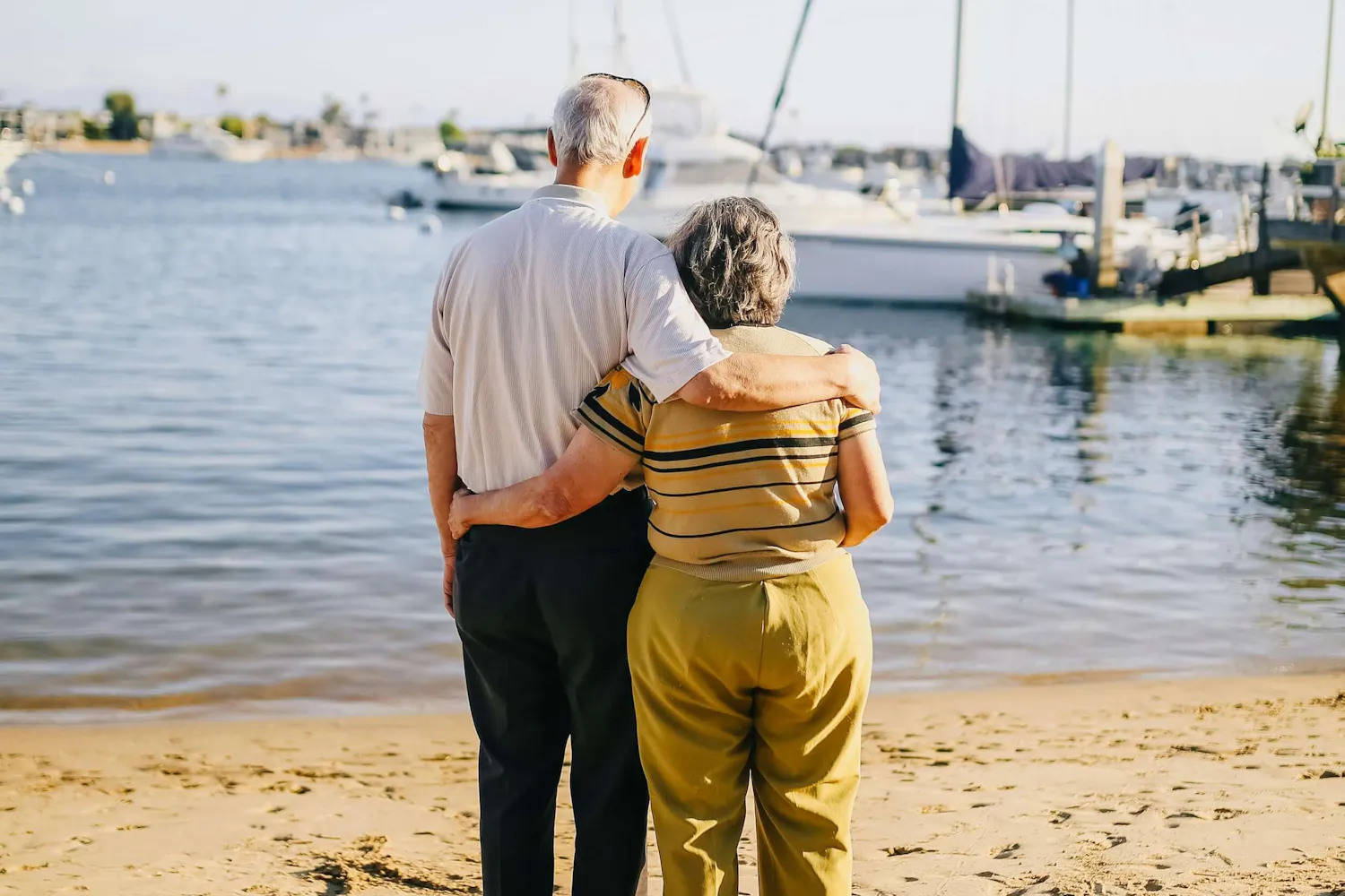 Älteres Pärchen steht Arm in Arm am Strand Älteres Pärchen steht Arm in Arm am Strand