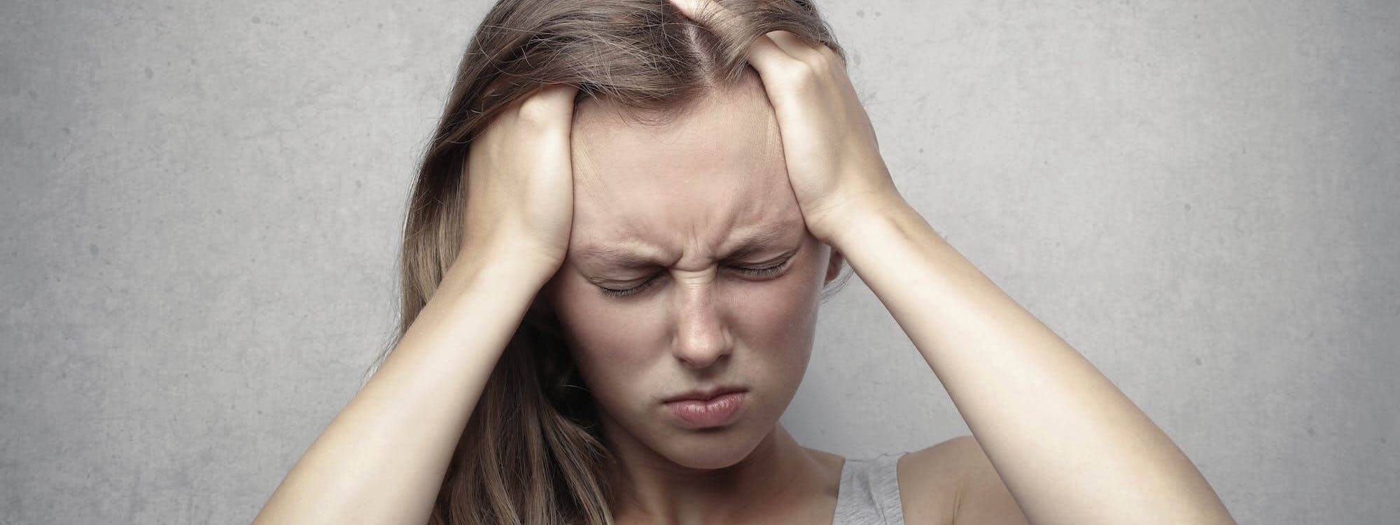Frau mit Schmerzen fasst sich an den Kopf