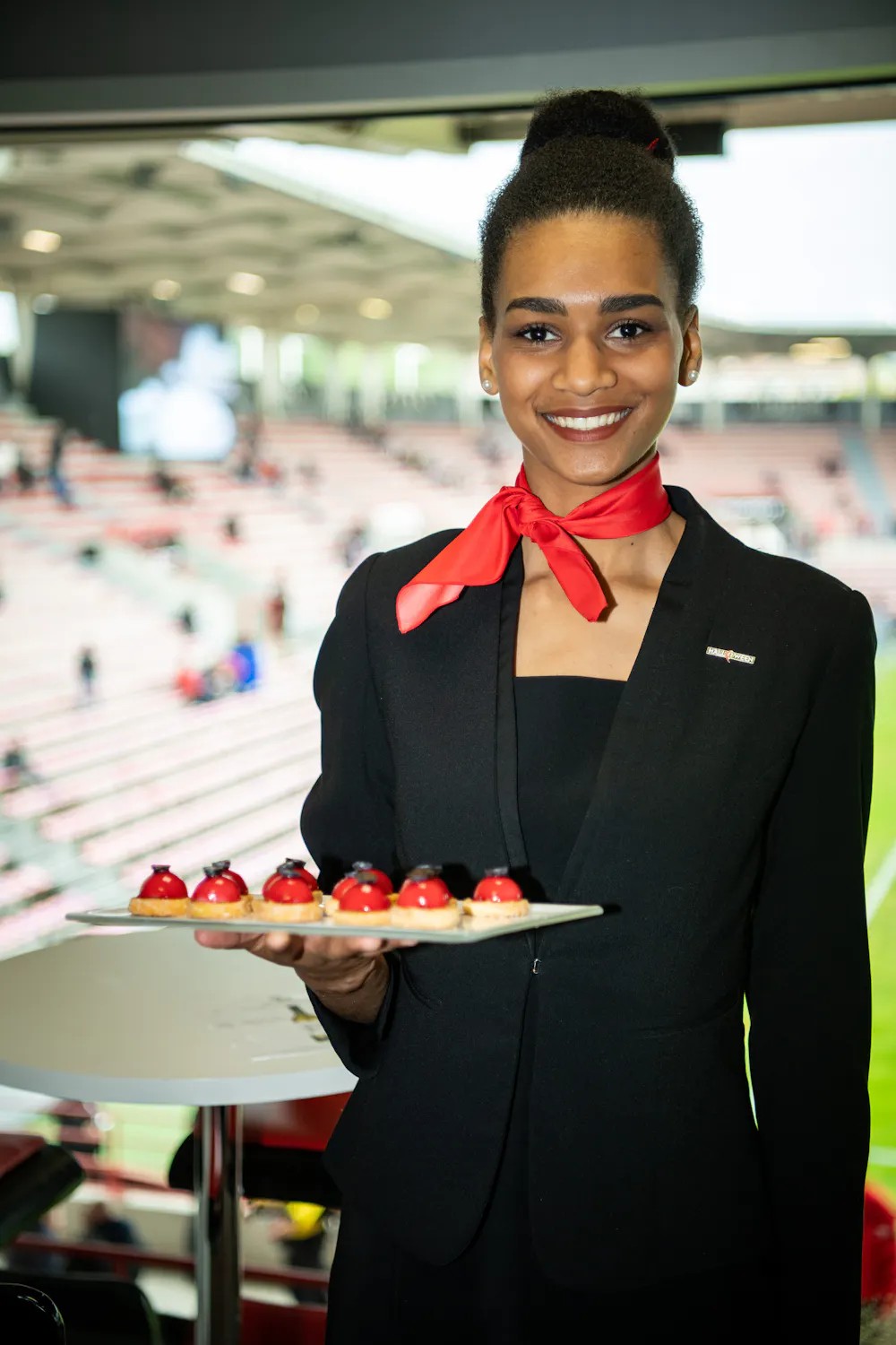 Hôtesse souriante assurant le service en loge VIP