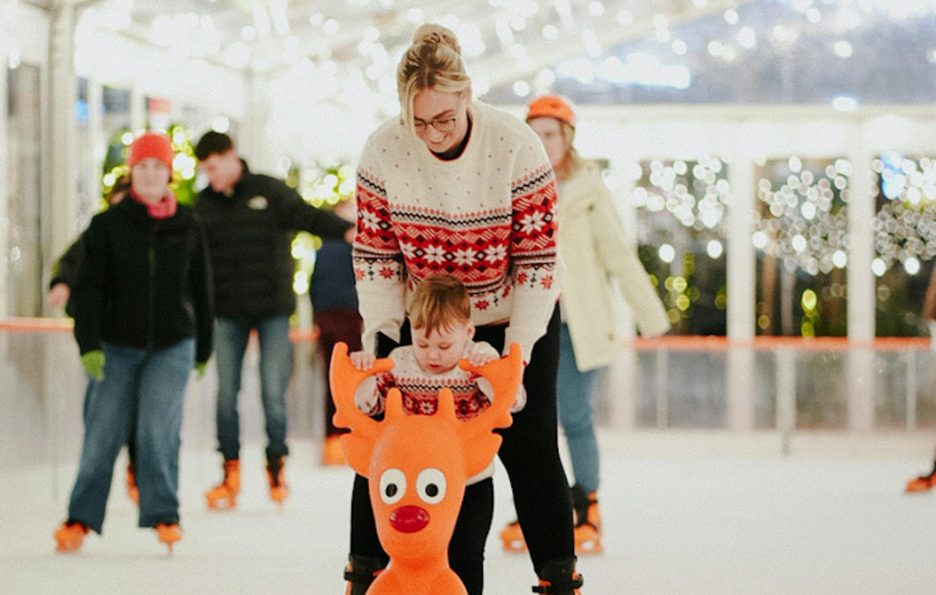 people ice skating on ice rink, with a Rudolph skating aid