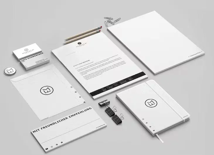 Weiße Geschäftsausstattung mit Briefbogen, Umschlag, Visitenkarten und weiteren abgestimmten Büroartikeln.
