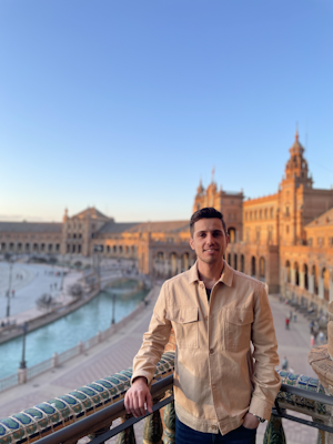 The author of the article with a background of a blue sky and some historical buildings.