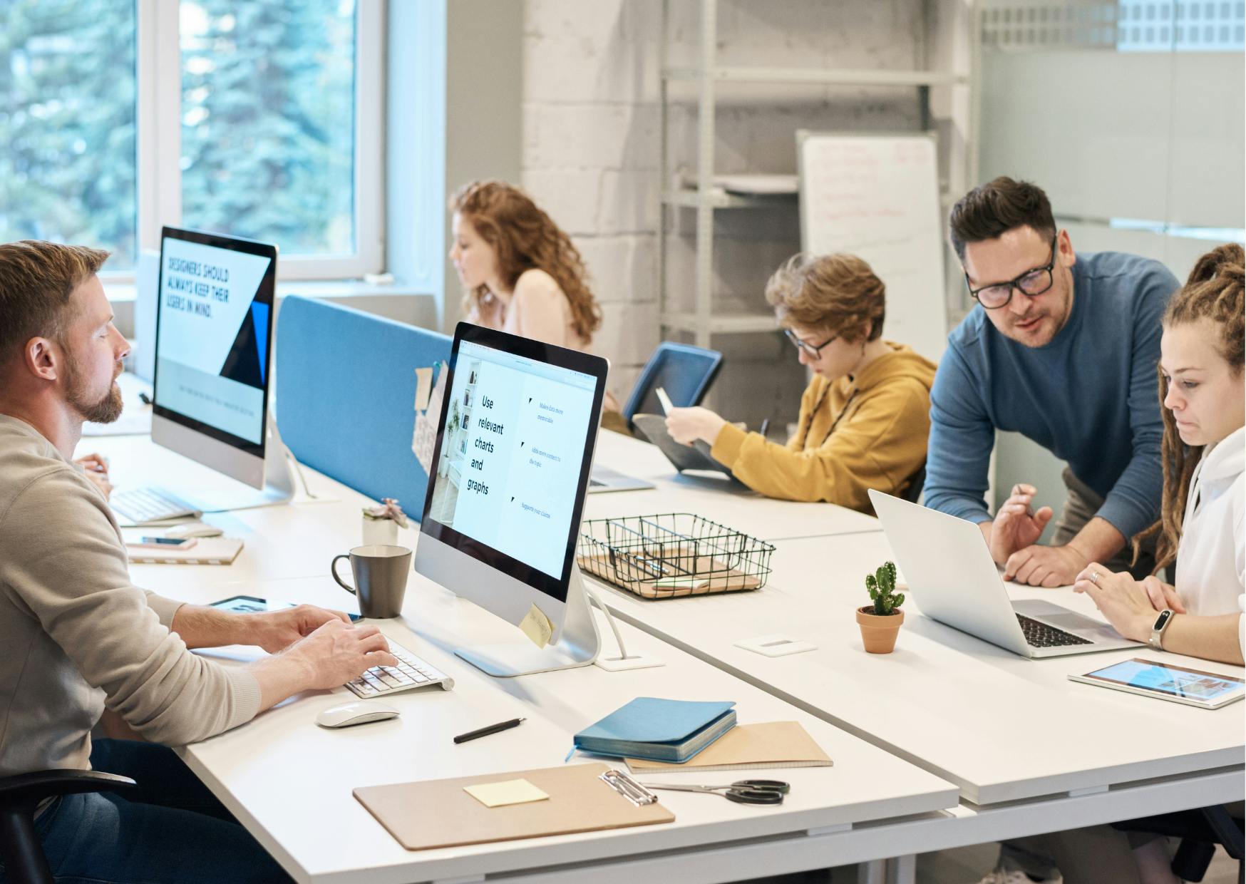 Five employees sitting around a large desk in an office environment.