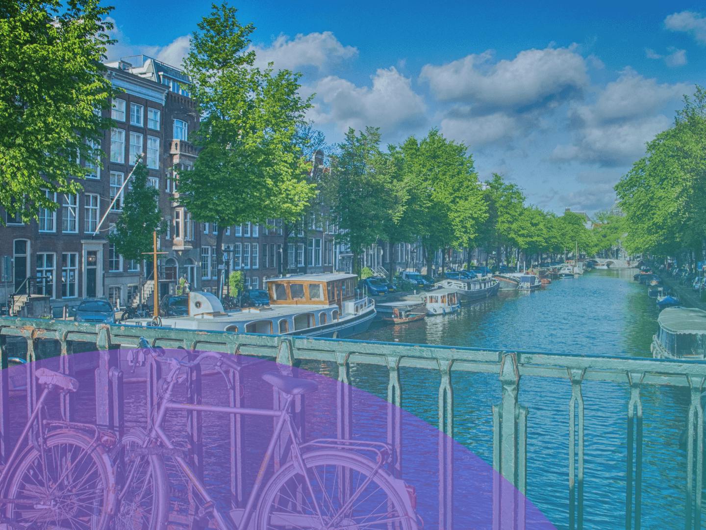 Hollanda'da kanalın, çitlere dayanmış bisikletlerin park edildiği küçük bir köprüden görünümü. 