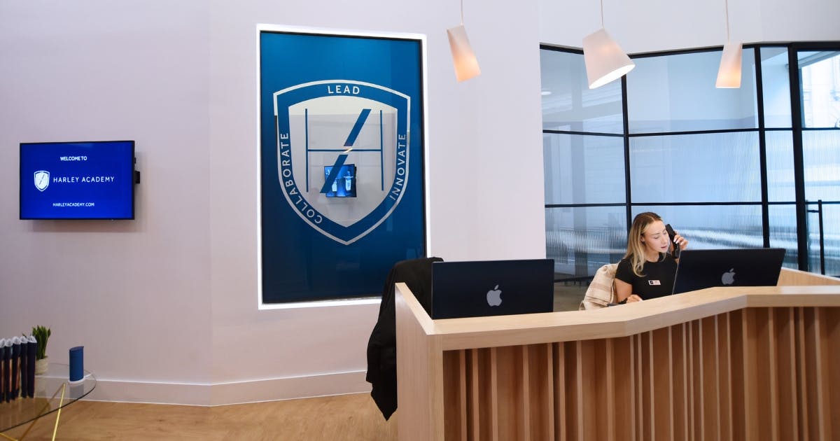 Harley Academy London venue hire - Reception space at Threadneedle Street featuring a fully-equipped reception desk, window into the auditorium and a customisable digital screen