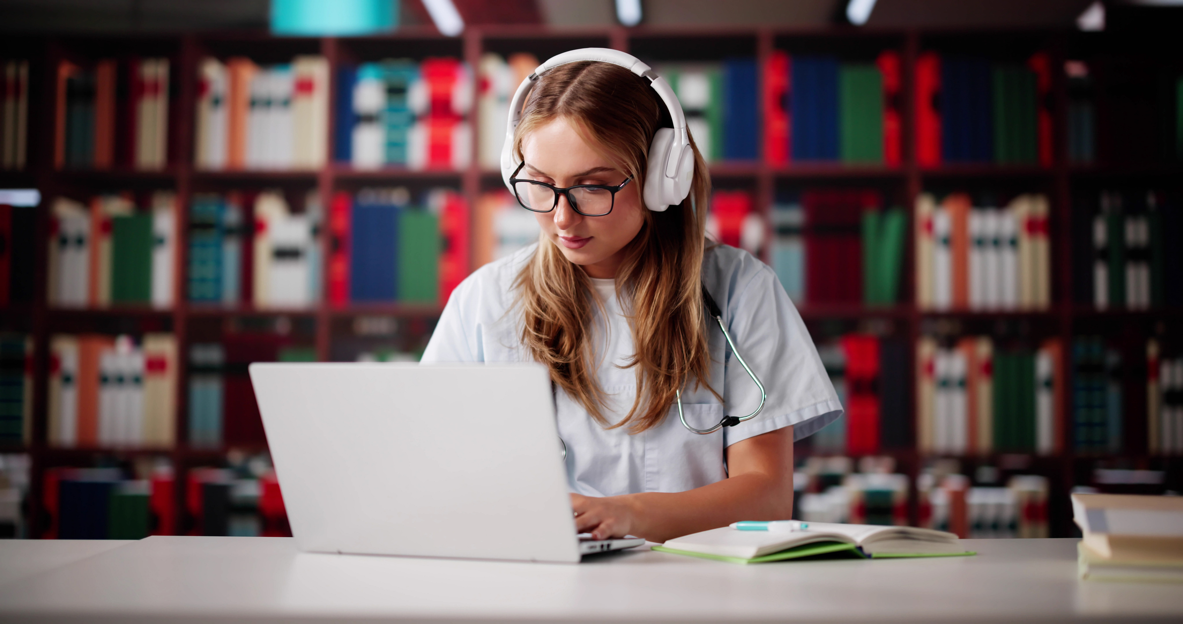 Female student with headphone on looking at something on her laptop