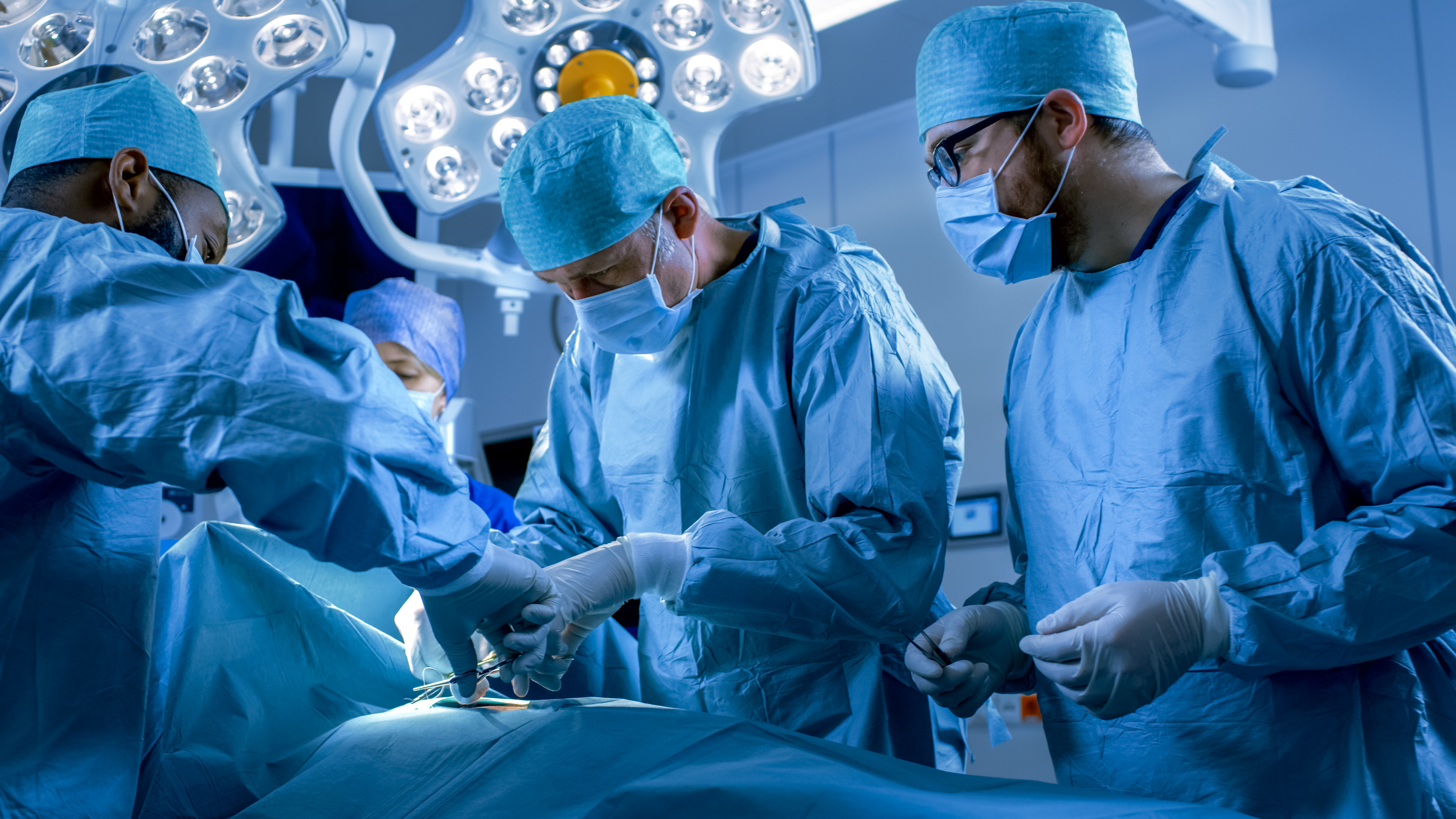Surgeons surrounding an operating table in an operating room