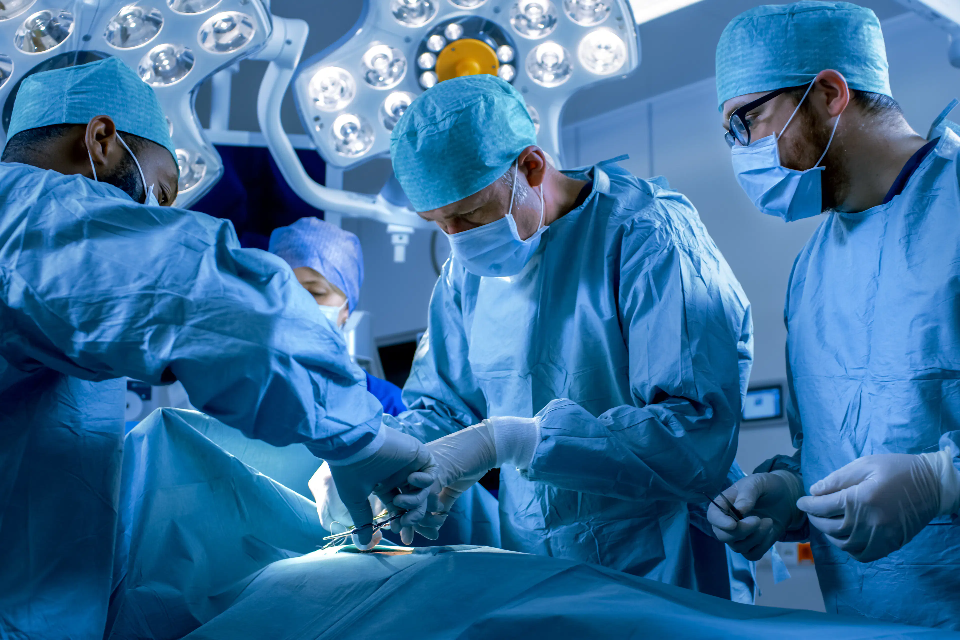 Surgeons surrounding an operating table in an operating room