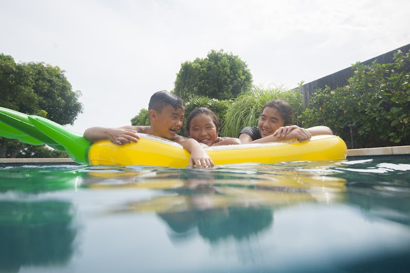 three children laughing in a pool