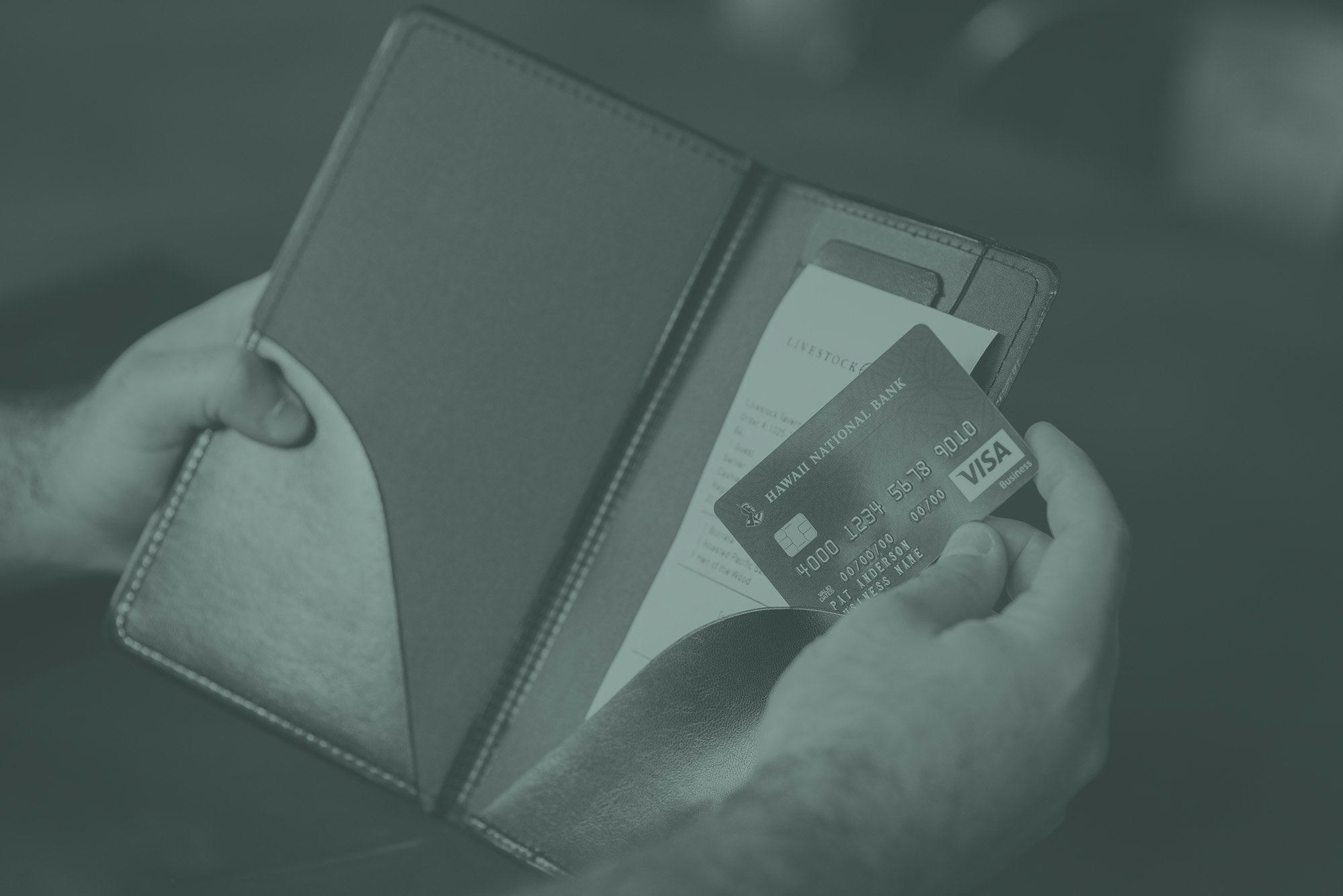 hands holding a restaurant tab and visa business credit card