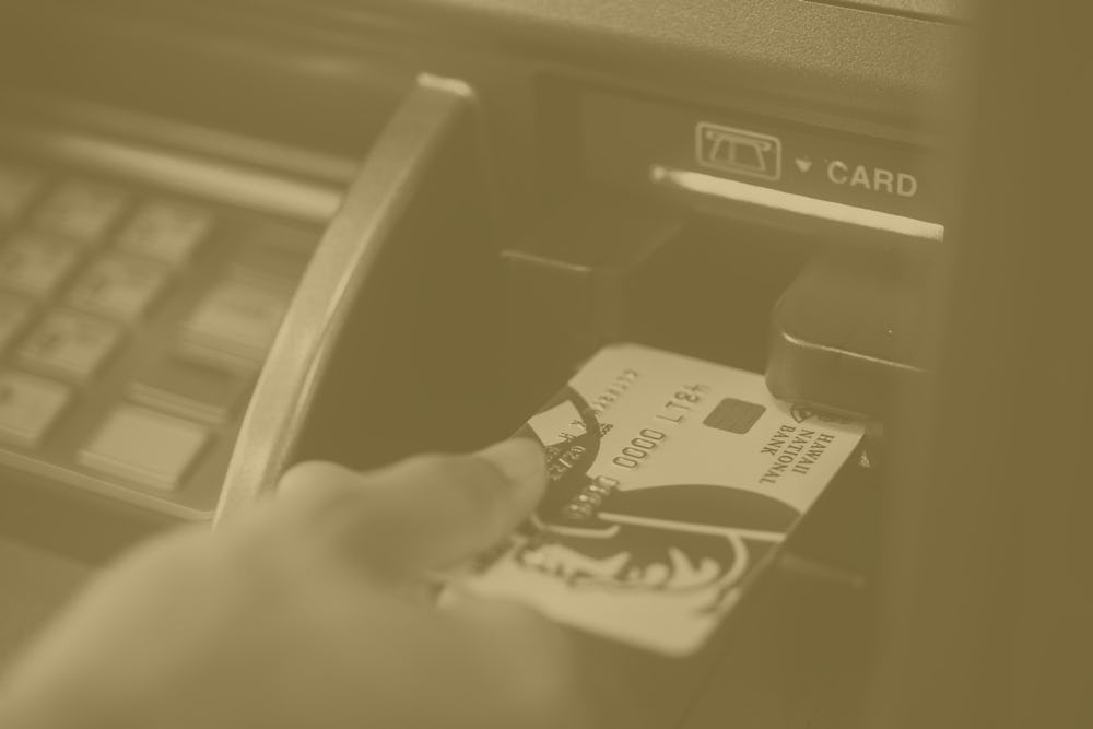 close up shot of hand inserting debit card into ATM