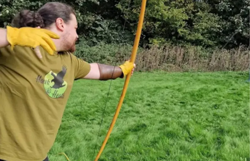 Person in Hawk and Heath logo t-shirt with firing an English longbow